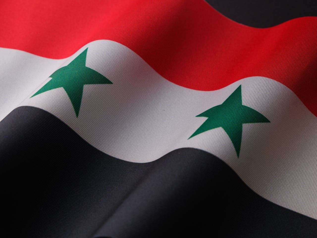 about-01 Close-up of the Syrian flag with detailed fabric texture showcasing patriotic symbolism.